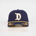 A navy blue baseball cap featuring a large white embroidered letter 'D' outlined in gold on the front, with gold embroidered details on the brim and a gold stripe along the edge, shown against a plain white background.
