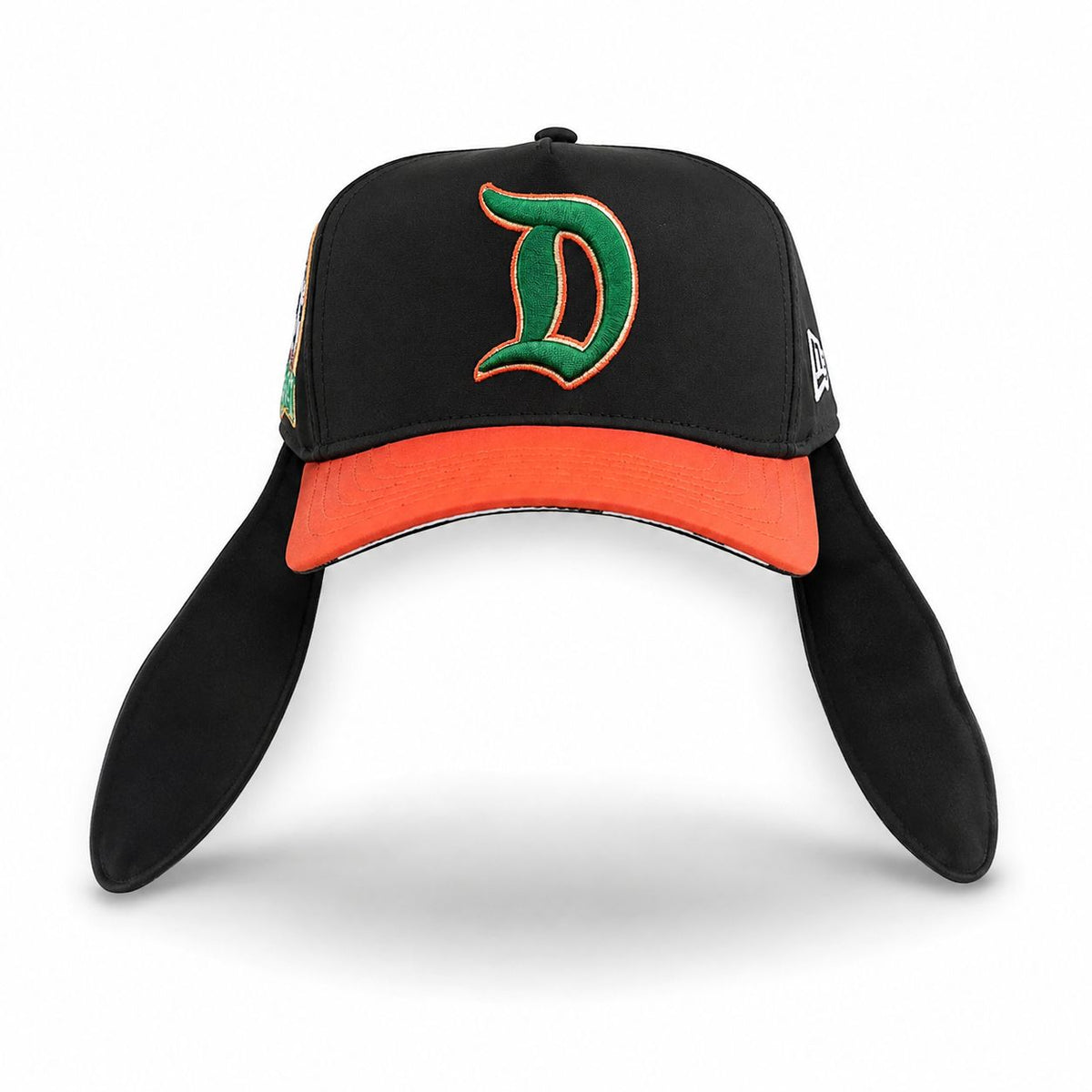 A black baseball cap with floppy ear flaps, featuring a bright orange visor and a green embroidered letter 'D' outlined in orange on the front. A white New Era flag logo is visible on the side.